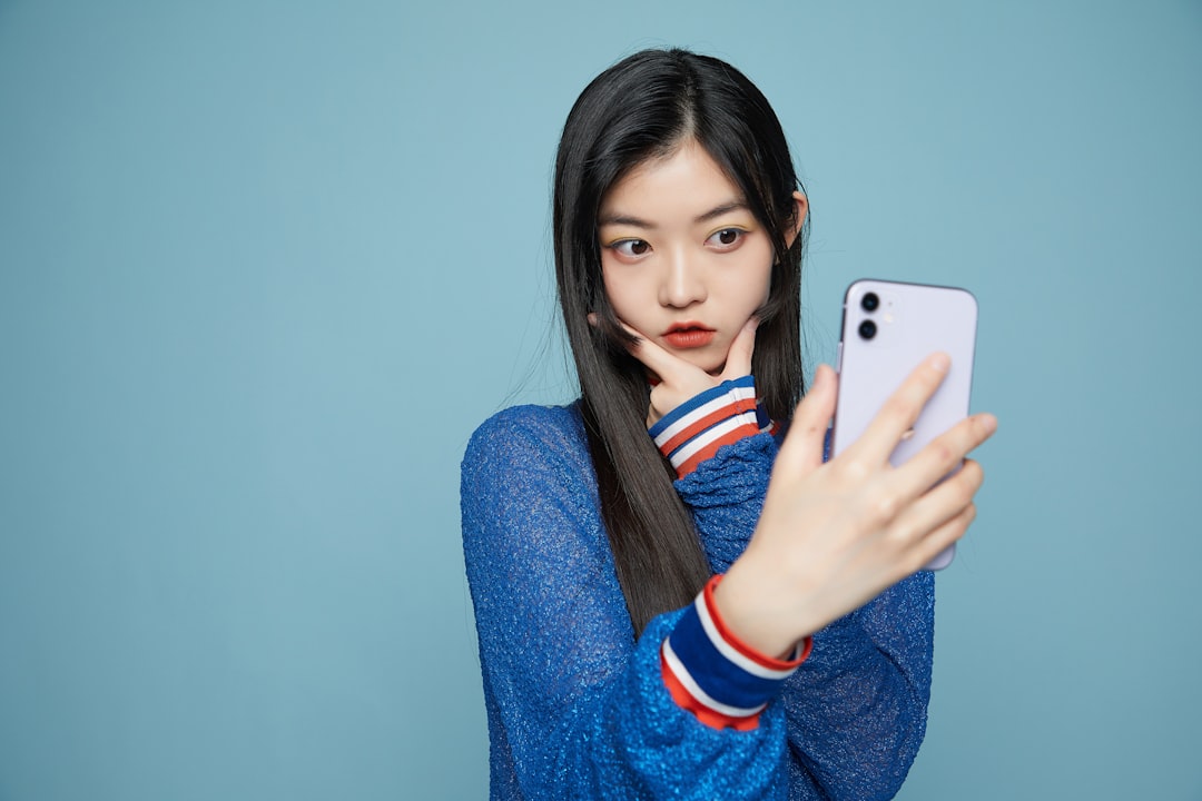 스마트폰으로 자신의 얼굴 사진을 확인하며 헤어스타일 앱을 사용하는 모습을 담은 이미지